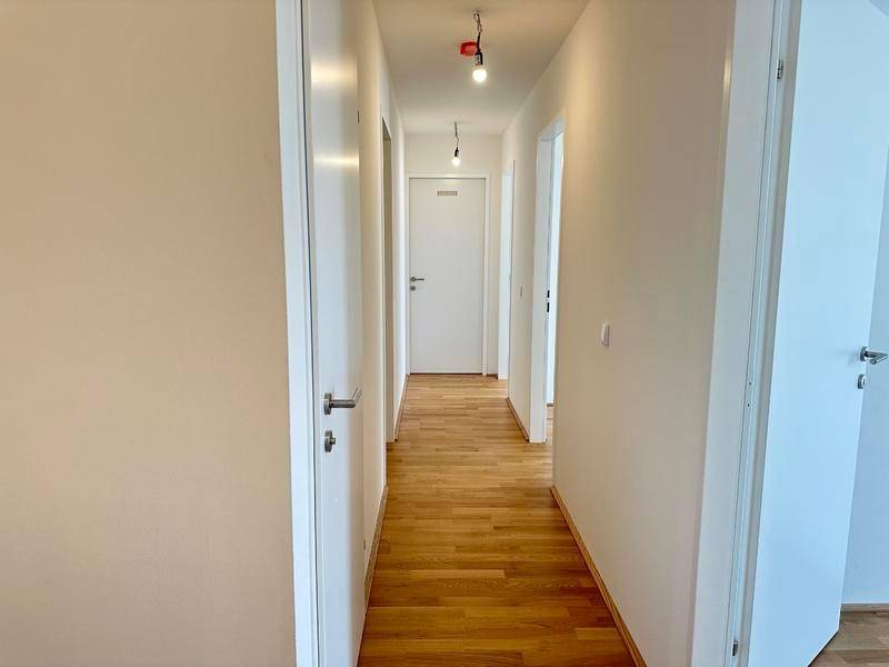 Heller Flur mit Holzboden und mehreren Türen, der verschiedene Räume verbindet.