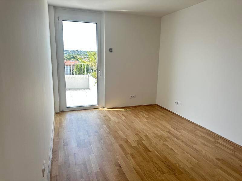 Helles Schlafzimmer mit Holzboden und Balkonzugang, ideal für erholsame Nächte.