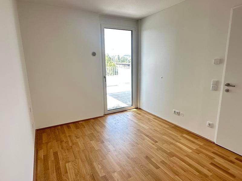 Helles Schlafzimmer mit Holzboden und direktem Zugang zu einem Außenbereich.