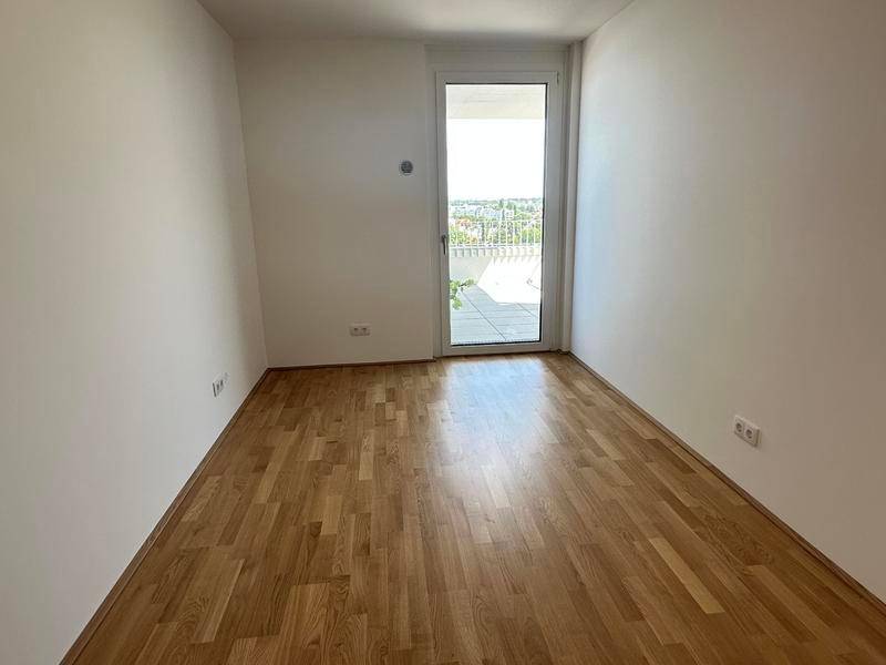 Helles Zimmer mit Parkettboden und Zugang zu einem Außenbereich.