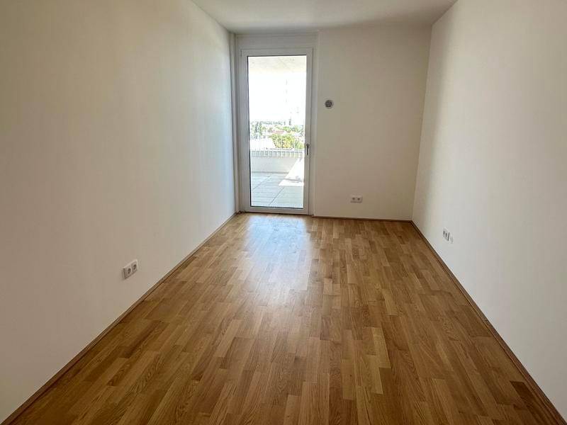 Helles Zimmer mit Parkettboden und direktem Zugang zu einem Außenbereich, vielseitig nutzbar.
