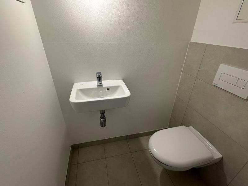 Kleines Gäste-WC mit Wand-WC und Handwaschbecken, praktisch und platzsparend gestaltet.