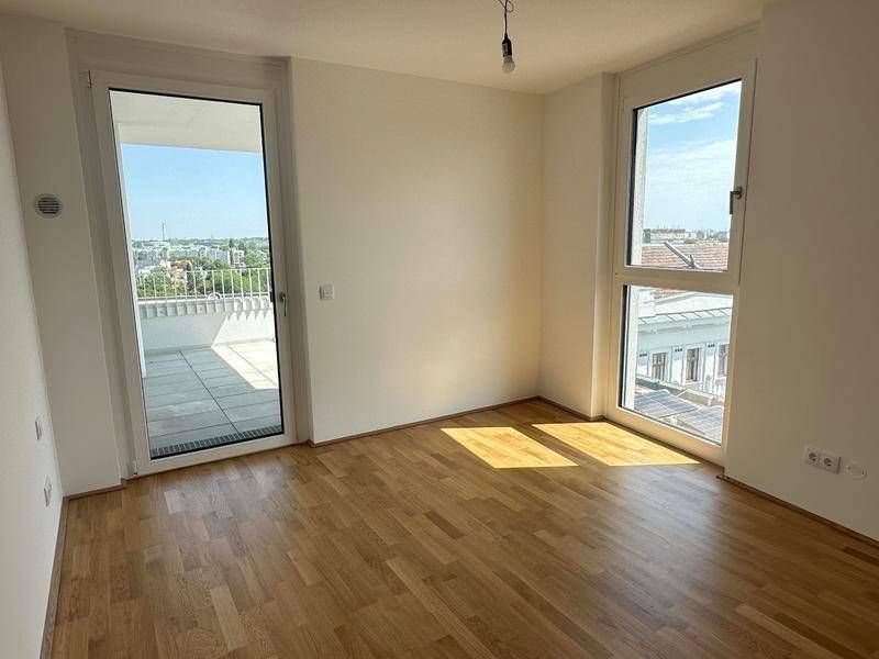 Helles Schlafzimmer mit Parkettboden und Zugang zu einem Balkon mit Stadtblick.