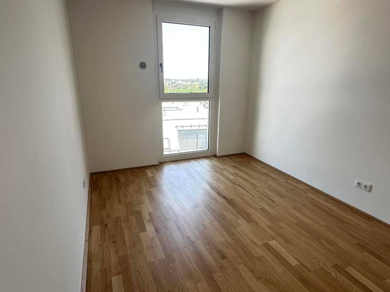 Kleines, helles Zimmer mit Parkettboden und Fenster mit Blick auf die Umgebung.