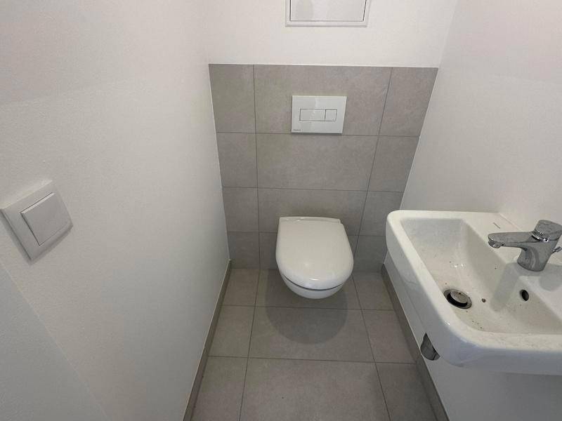 Kleines Gäste-WC mit wandhängender Toilette und einem kompakten Waschbecken.