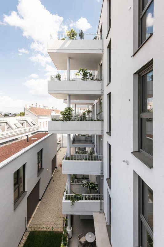 Vertikale Ansicht der Balkone eines modernen Wohngebäudes mit Pflanzen und Stadtblick.