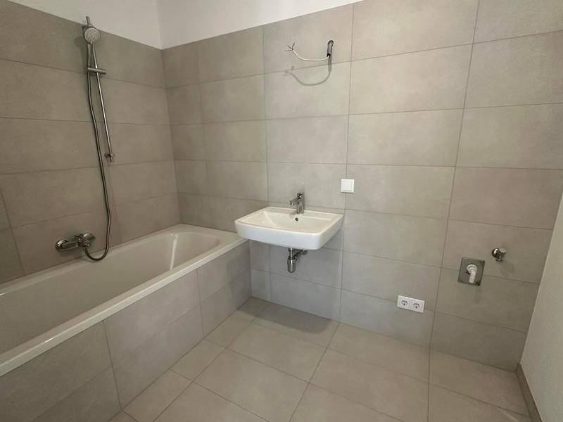Modernes Badezimmer mit Badewanne, Duscharmatur und einem einzelnen Waschbecken.