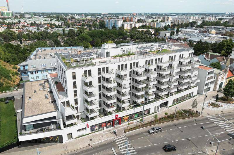 Weitläufige Luftaufnahme des modernen Wohnkomplexes mit umliegender Infrastruktur und Stadtblick.