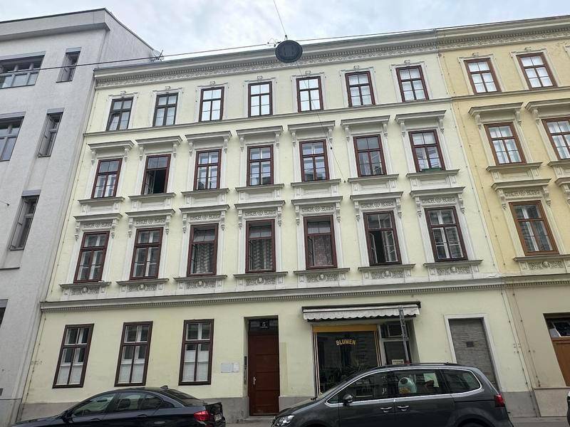 Klassische Fassade eines Mehrfamilienhauses mit vielen Fenstern und traditionellen Details.