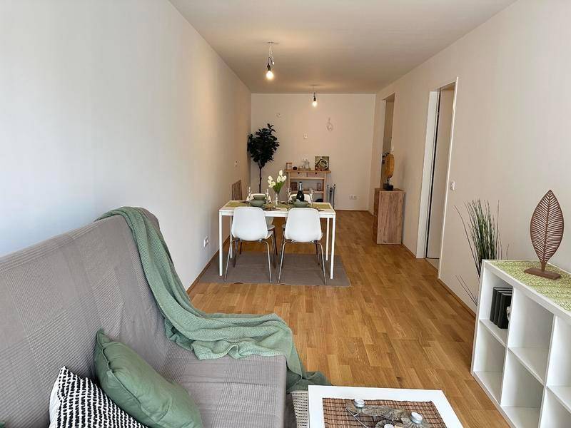Gemütlicher Wohn- und Essbereich mit Holzboden und moderner Einrichtung.