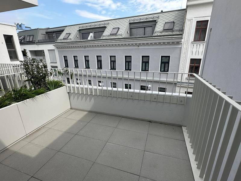 Geräumiger Balkon mit Fliesenboden und Blick auf die umliegenden Gebäude.