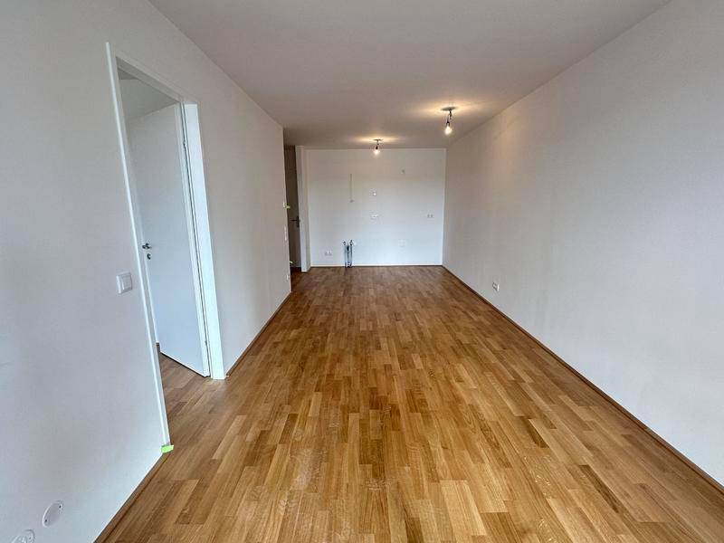 Leerer Raum mit Holzboden und weißen Wänden, bereit für die individuelle Gestaltung.