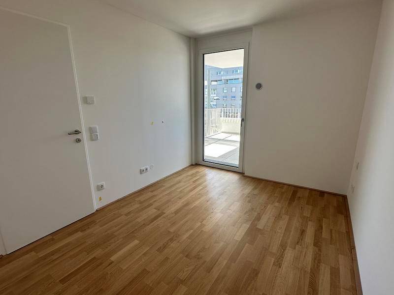 Schlafzimmer mit Holzboden und direktem Zugang zu einem privaten Balkon.