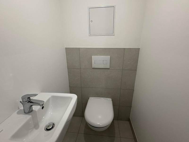 Kompaktes Gäste-WC mit wandhängender Toilette und kleinem Waschbecken.