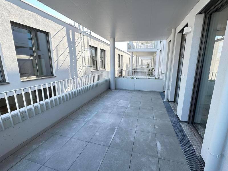 Geräumige Loggia mit modernem Fliesenboden und Blick auf die umliegenden Gebäude.