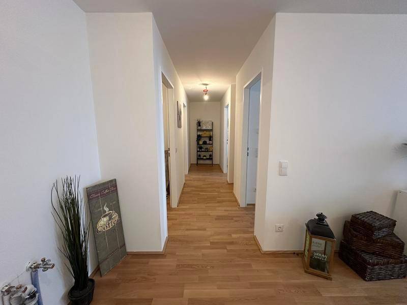 Langer, heller Flur mit Holzparkett, der zu den verschiedenen Räumen führt.