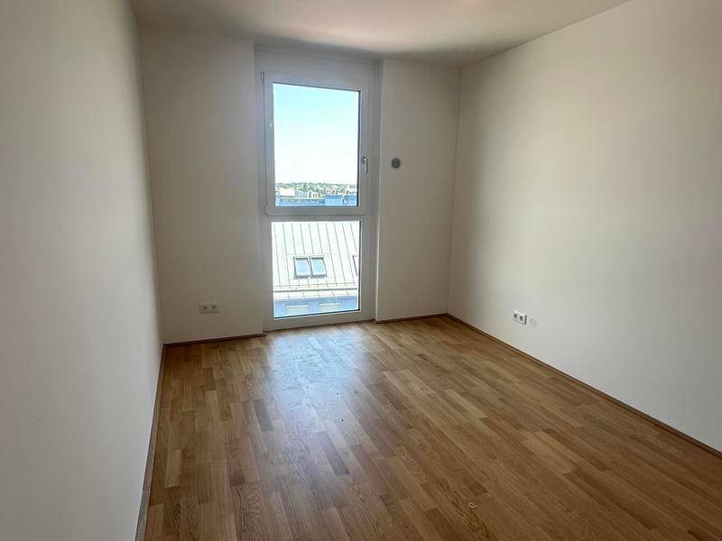 Unmöbliertes Zimmer mit Holzboden und großem Fenster, ideal als Schlaf- oder Arbeitszimmer.