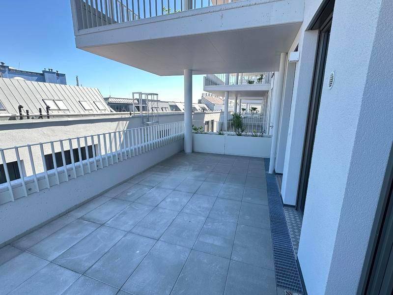 Geräumige Terrasse mit Fliesenboden und Blick auf die umliegenden Dächer der Stadt.