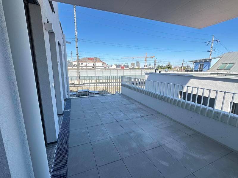 Große geflieste Terrasse mit Metallgeländer und Blick auf die Stadt und Industrieanlagen.
