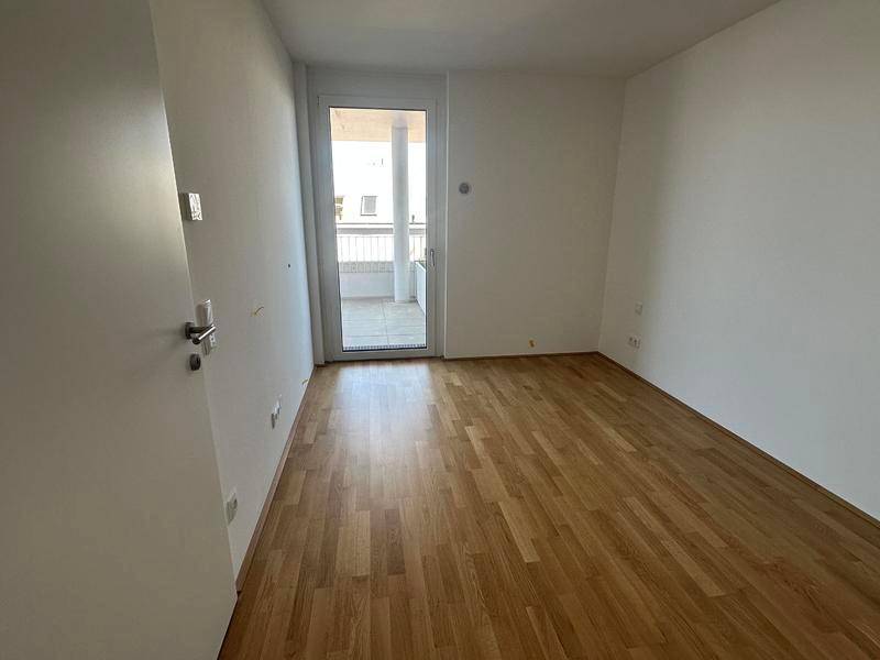 Helles Schlafzimmer mit Parkettboden und direktem Zugang zu einem Außenbereich.