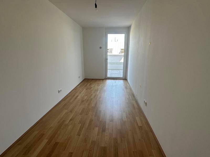 Geräumiges, helles Zimmer mit Parkettboden und Fensterfront zum Außenbereich.