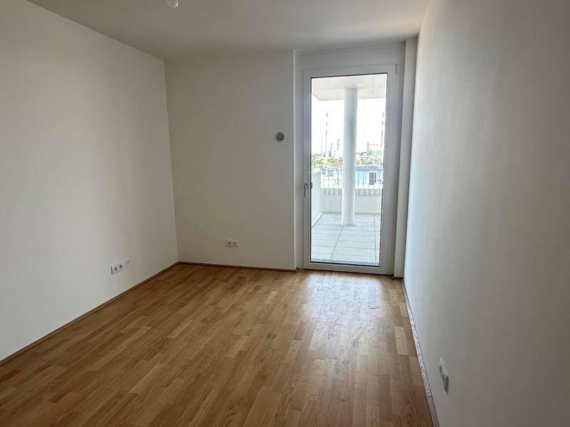 Helles Schlafzimmer mit Holzboden und direktem Zugang zu einem Balkon oder einer Terrasse.