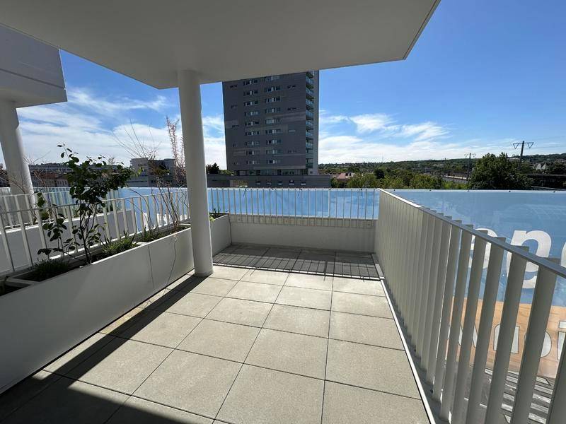 Geräumiger Balkon mit Fliesenboden und Blick auf die umliegende Stadtbebauung.