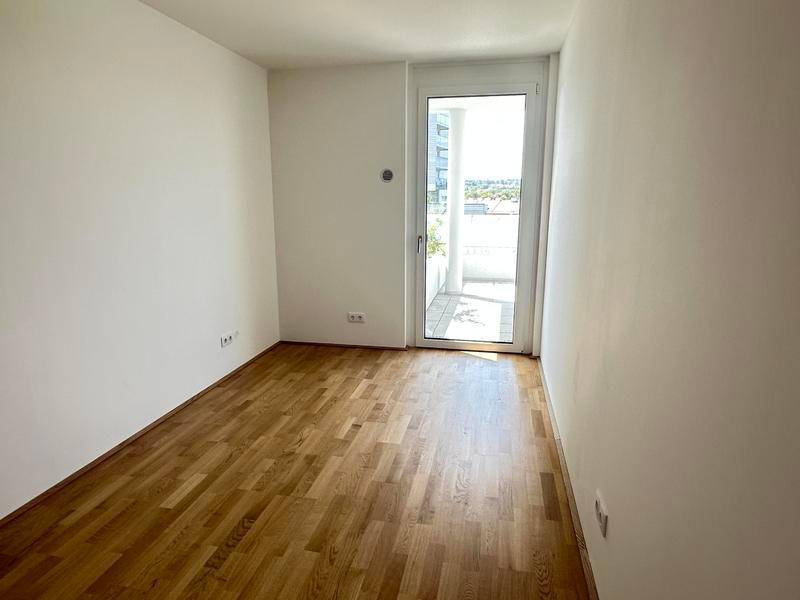 Helles Zimmer mit Holzboden und direktem Zugang zu einem Außenbereich.