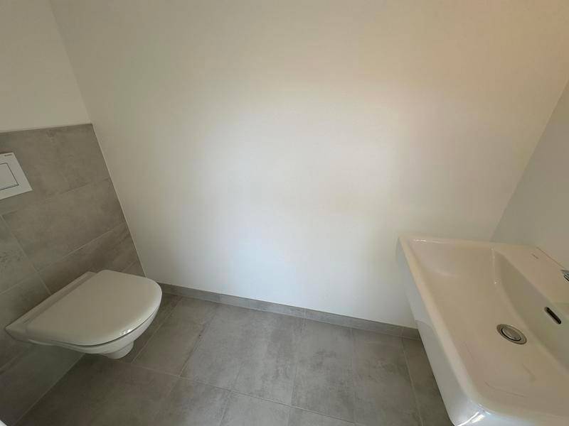 Separate Gästetoilette mit Wand-WC und kleinem Waschbecken in modernem Design.