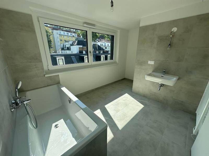 Modernes Badezimmer mit Badewanne, Waschbecken und grauen Fliesen.