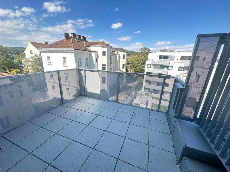 Geräumige Dachterrasse mit Fliesenboden und Blick auf die umliegenden Gebäude.