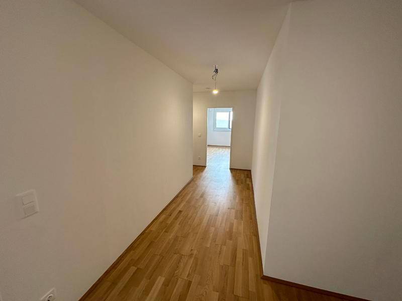 Langer, heller Flur mit Holzfußboden, der den Zugang zu den einzelnen Zimmern ermöglicht.