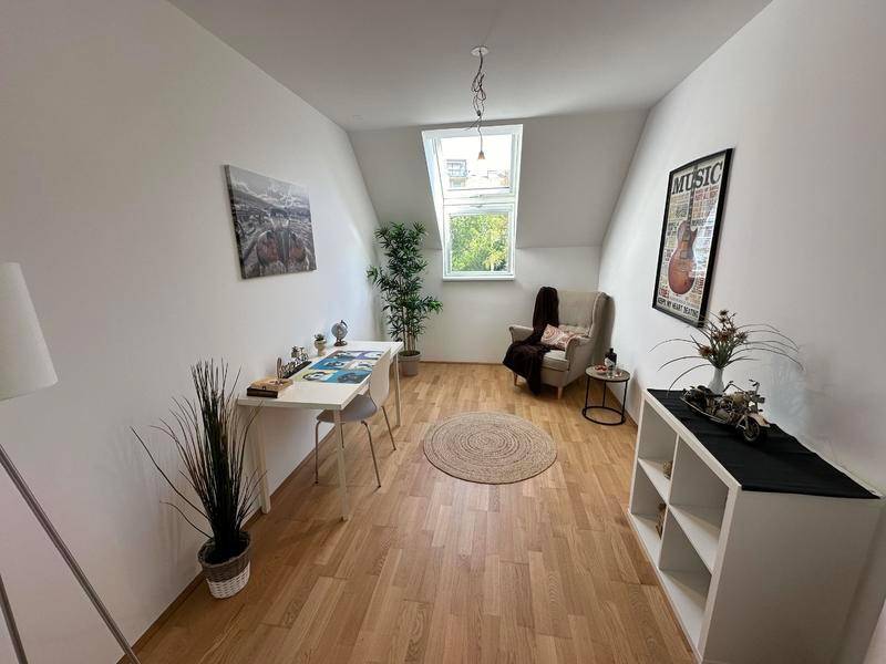Helles Arbeitszimmer mit Dachschräge, Holzboden und Dachfenster, modern eingerichtet.