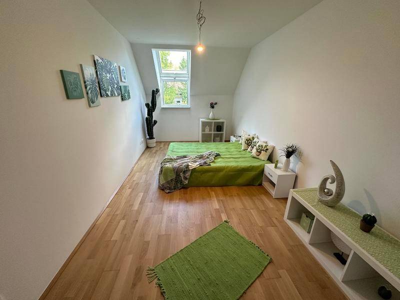 Schlafzimmer mit Dachschräge, Holzboden und Dachfenster, modern und hell eingerichtet.
