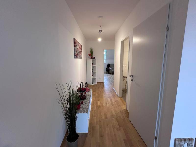 Langer, heller Flur mit Holzboden und schlichter, moderner Einrichtung.
