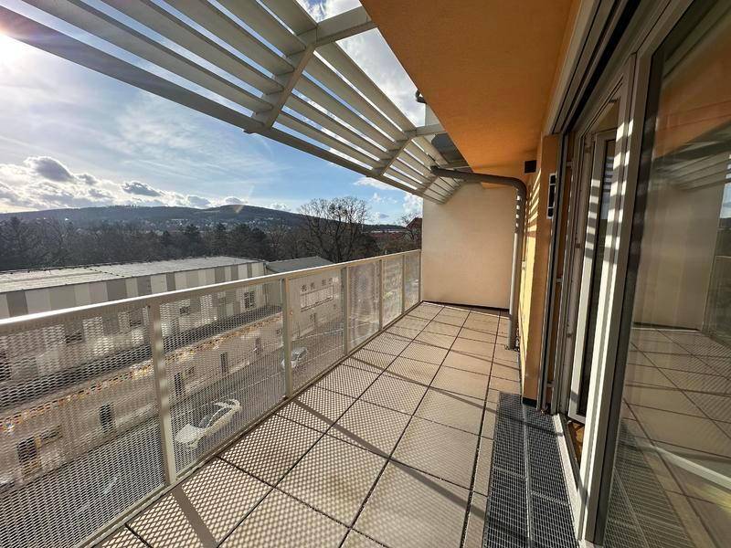 Sonniger Balkon mit moderner Metallbrüstung und weitem Blick über die Stadt und Hügel.