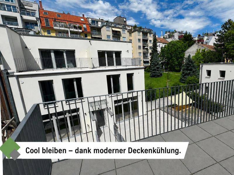 Blick von einem Balkon auf den begrünten Innenhof und umliegende Wohngebäude.