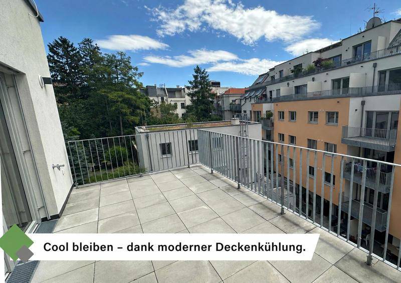 Geräumiger Balkon mit Fliesenboden und Metallgeländer, umgeben von Gebäuden und Bäumen.