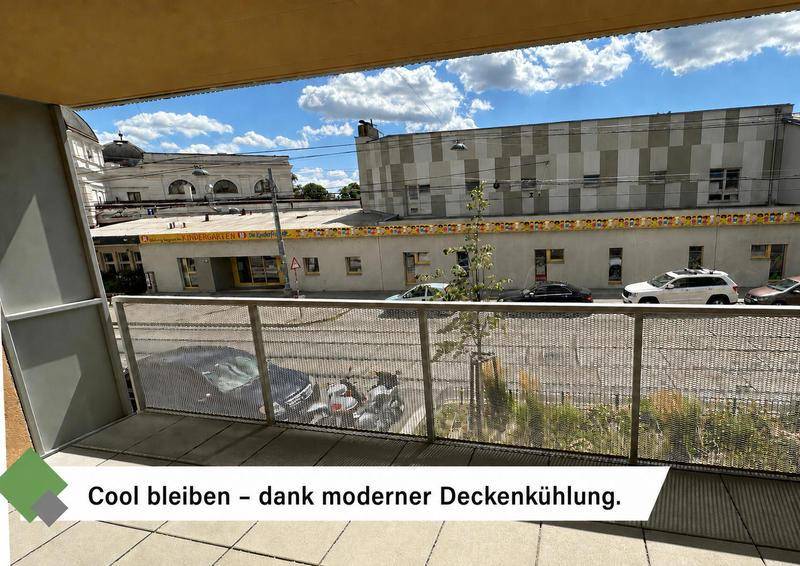 Balkon mit Metallgeländer und Blick auf die Straße sowie umliegende Gebäude.