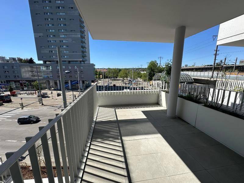 Geräumiger Balkon mit Fliesenboden und Blick auf die Stadt und umliegende Gebäude.