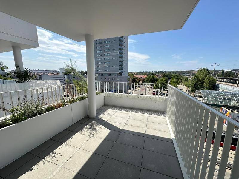 Heller Balkon mit Fliesenboden, weißen Geländern und Blick auf die Stadt.