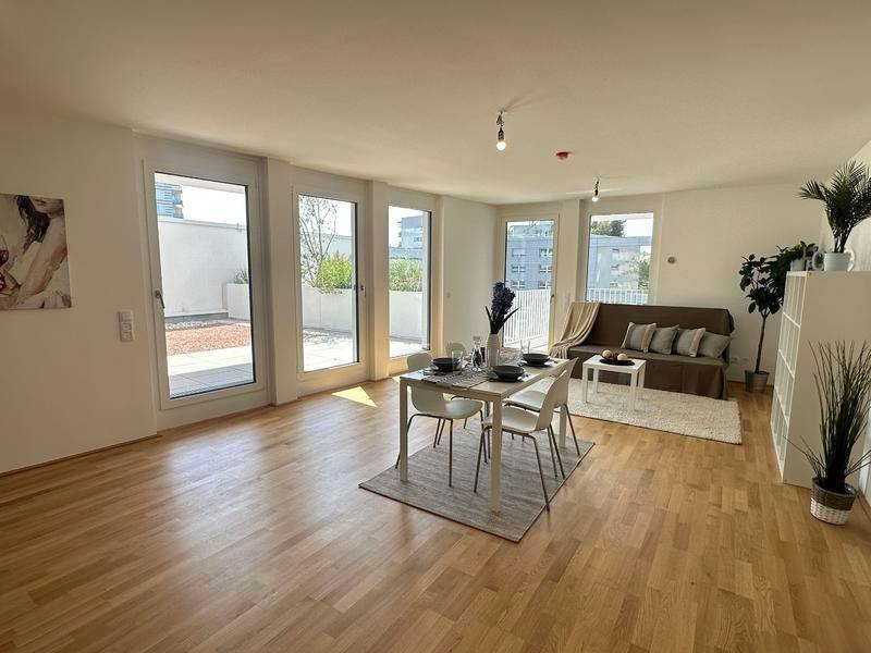 Heller Wohn- und Essbereich mit Holzboden, Esstisch und Zugang zu einer großzügigen Terrasse.