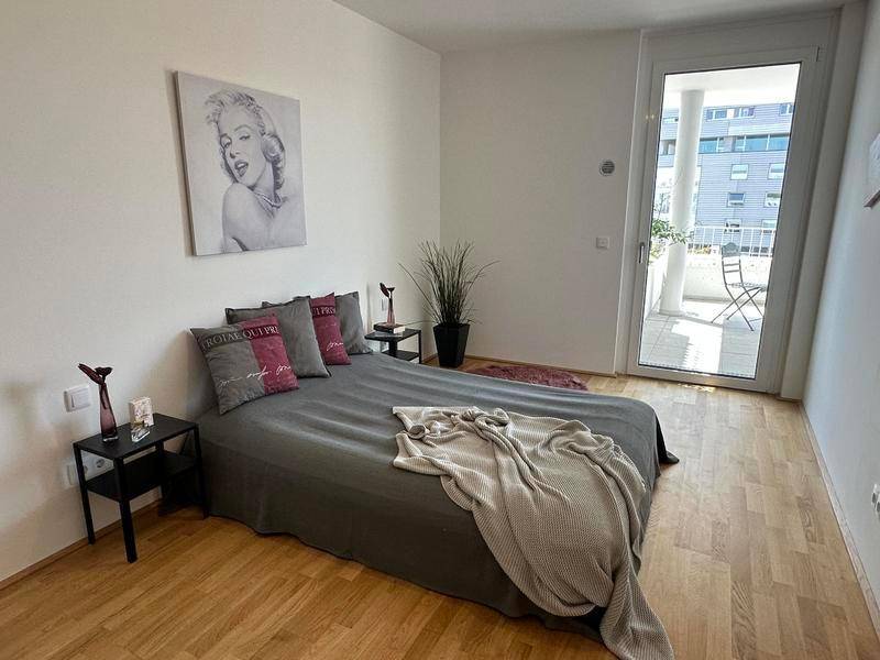 Gemütliches Schlafzimmer mit Holzboden, Doppelbett und direktem Zugang zu einem Balkon.