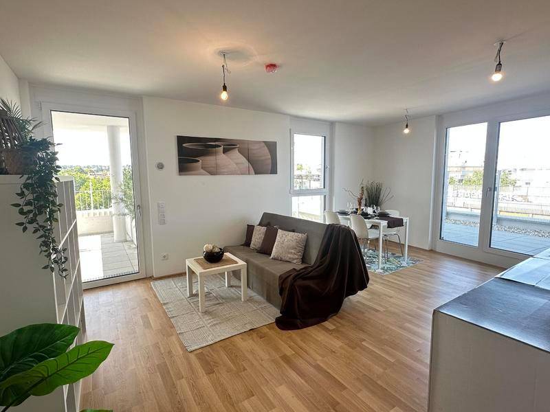 Heller Wohn-Essbereich mit Holzfußboden, gemütlichem Sofa und Zugang zu einem sonnigen Balkon.