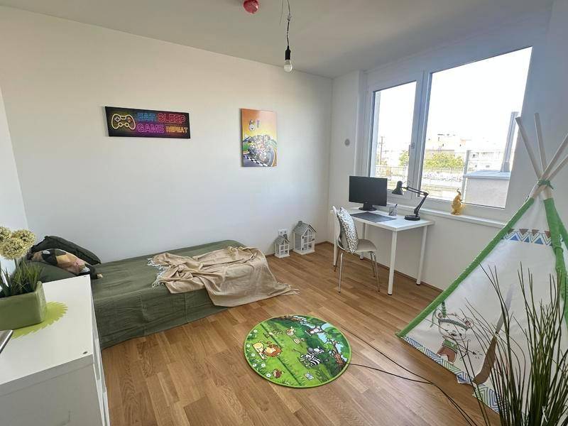 Kinderzimmer mit Holzboden, Schreibtisch und Spielbereich, hell und freundlich eingerichtet.