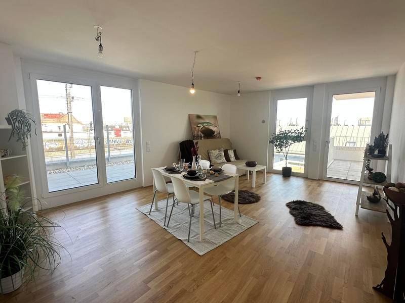 Heller Wohn- und Essbereich mit Holzboden, großen Fenstern und direktem Zugang zur Terrasse.
