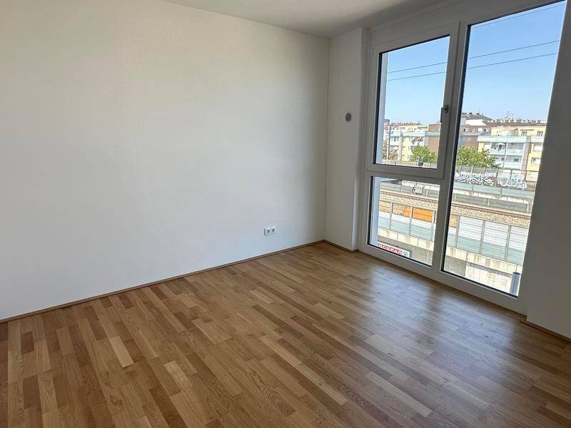 Ruhiges Schlafzimmer mit Parkettboden und großem Fenster mit Blick auf die Umgebung.