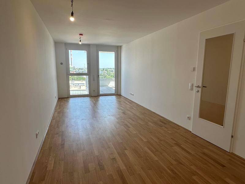 Heller Wohnraum mit Parkettboden und Zugang zu einem Balkon, bereit zur individuellen Gestaltung.