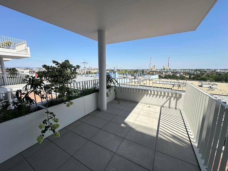 Geräumiger Balkon mit Fliesenboden und weitem Blick über die Stadt und Industrieanlagen.