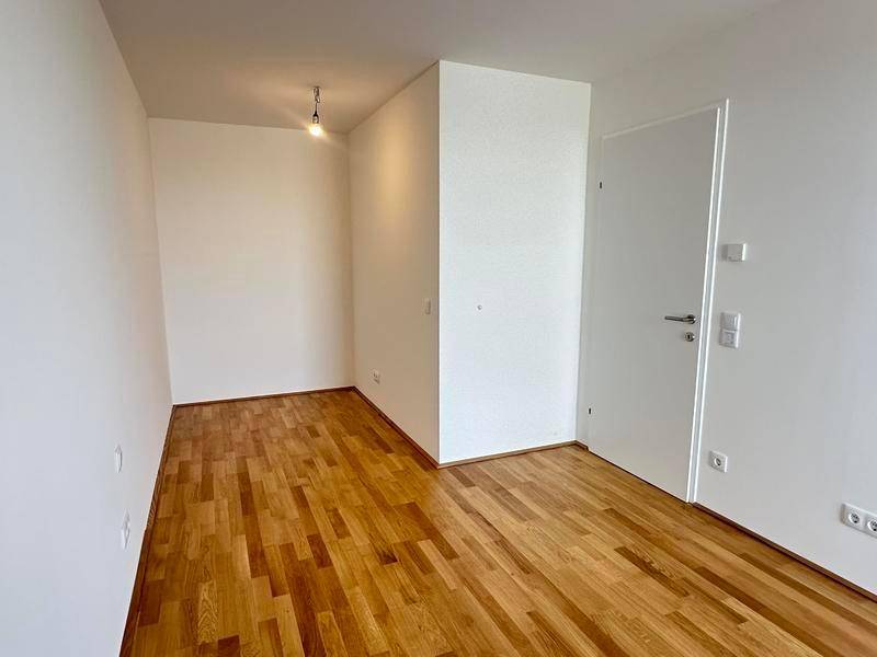 Leerer Raum mit Parkettboden und weißen Wänden, vielseitig nutzbar.